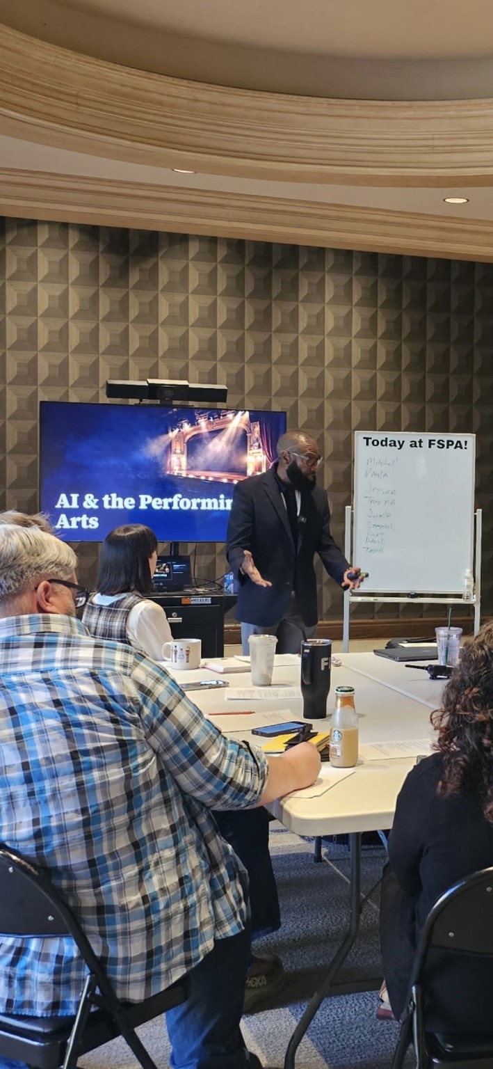 Roy McCloud presenting “AI & the Performing Arts” to leaders seated around a table at the Flint School of Performing Arts